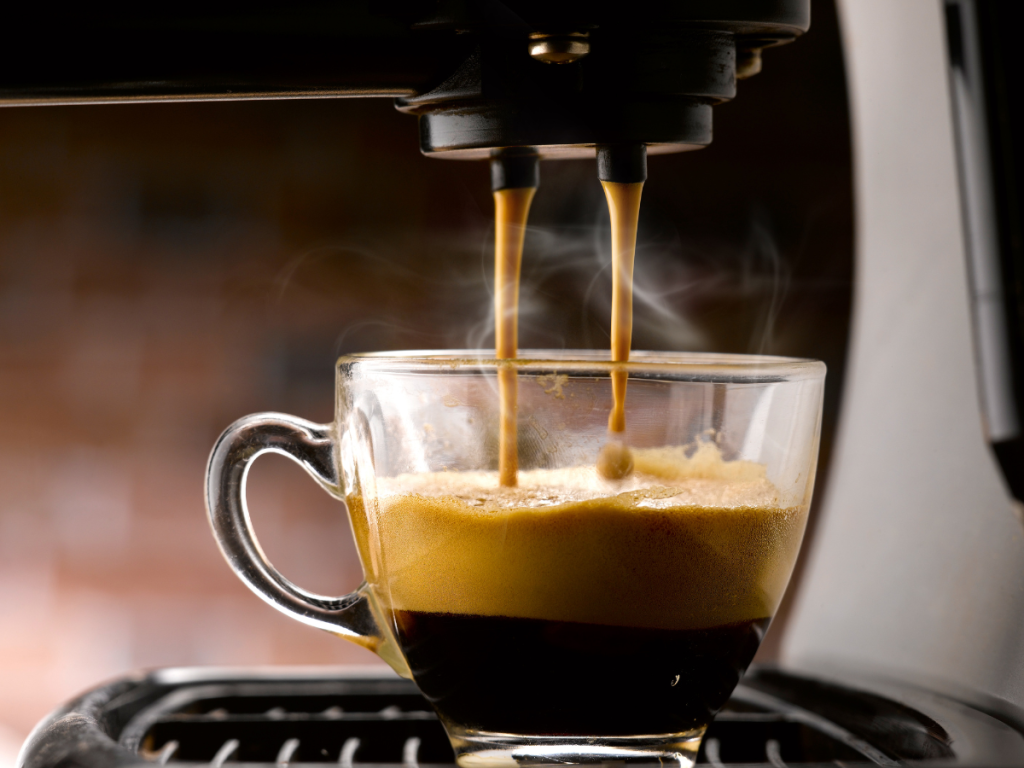 Extraction heads of a espresso machine filling a glass cup
