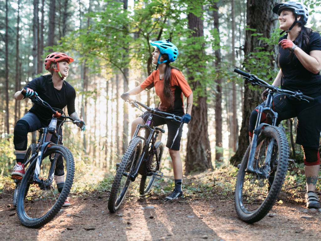 Group of female mountain bikers in the woods laughing