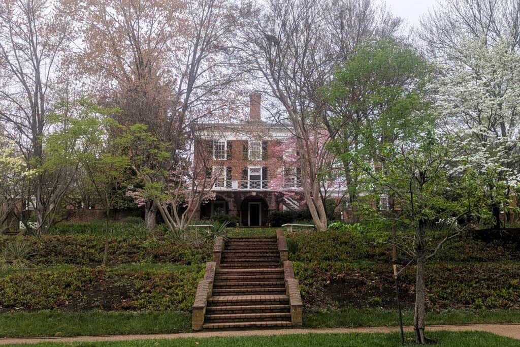 A large brick house with a tree in bloom in front of it.