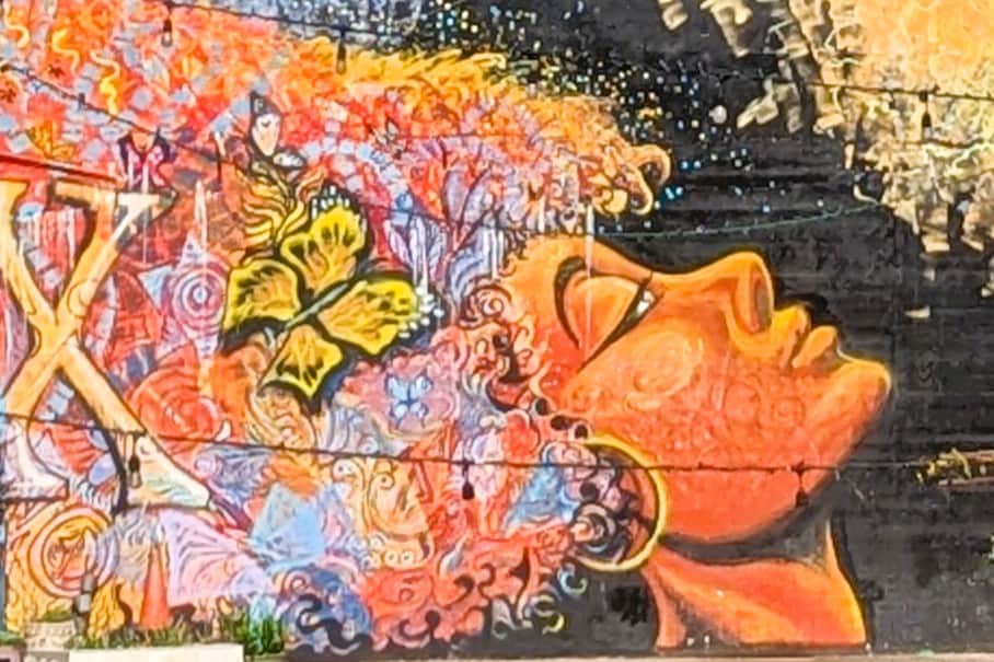 A colorful mural on a wall with a woman's face and curly hair.
