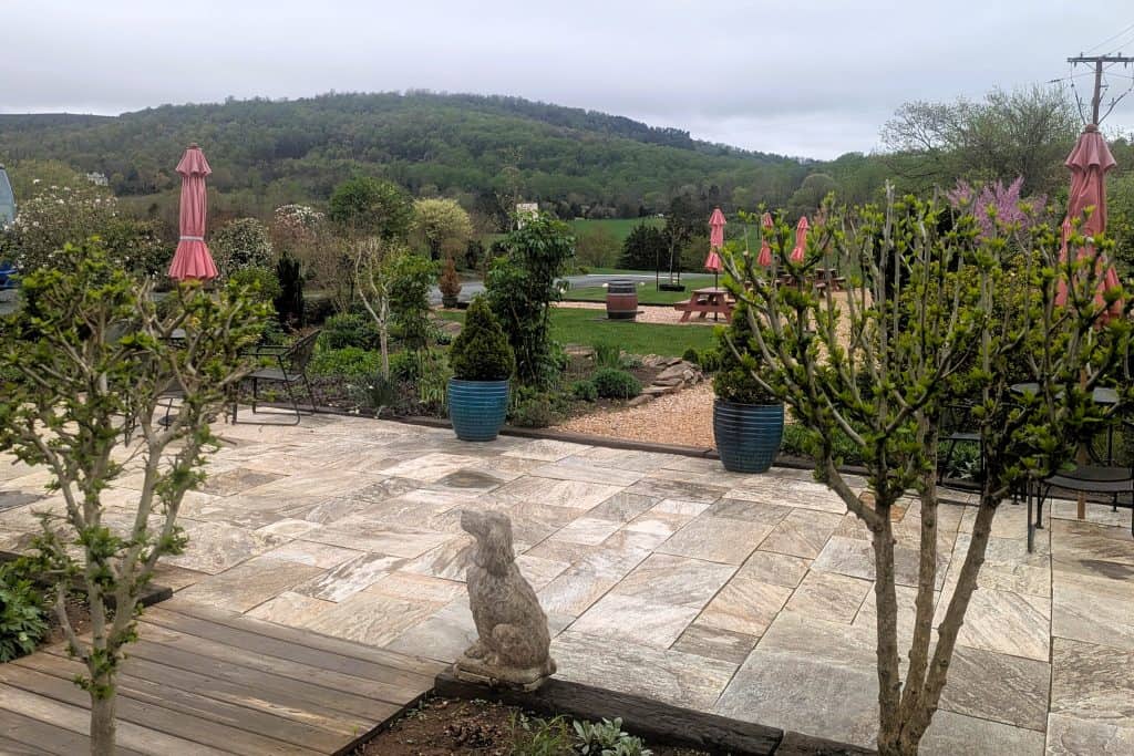 A patio with a stone wall and a garden.