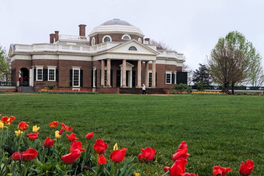 The front of a large brick building (Monticello) with red and yellow tulips.