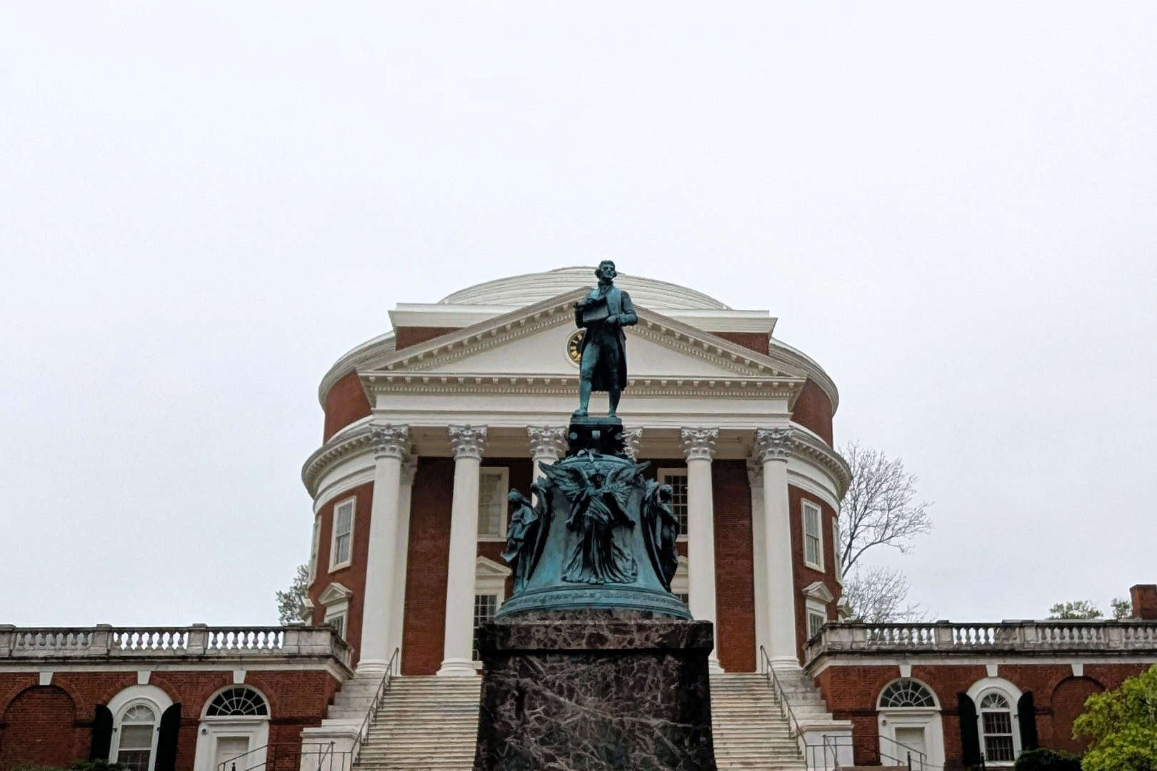 A statue of a man standing in front of a domed building.