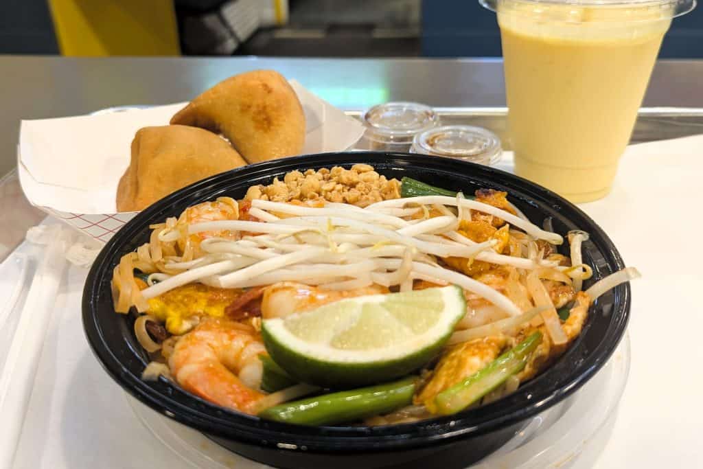 A bowl of Pad Thai with shrimp, noodles, and a lime.
